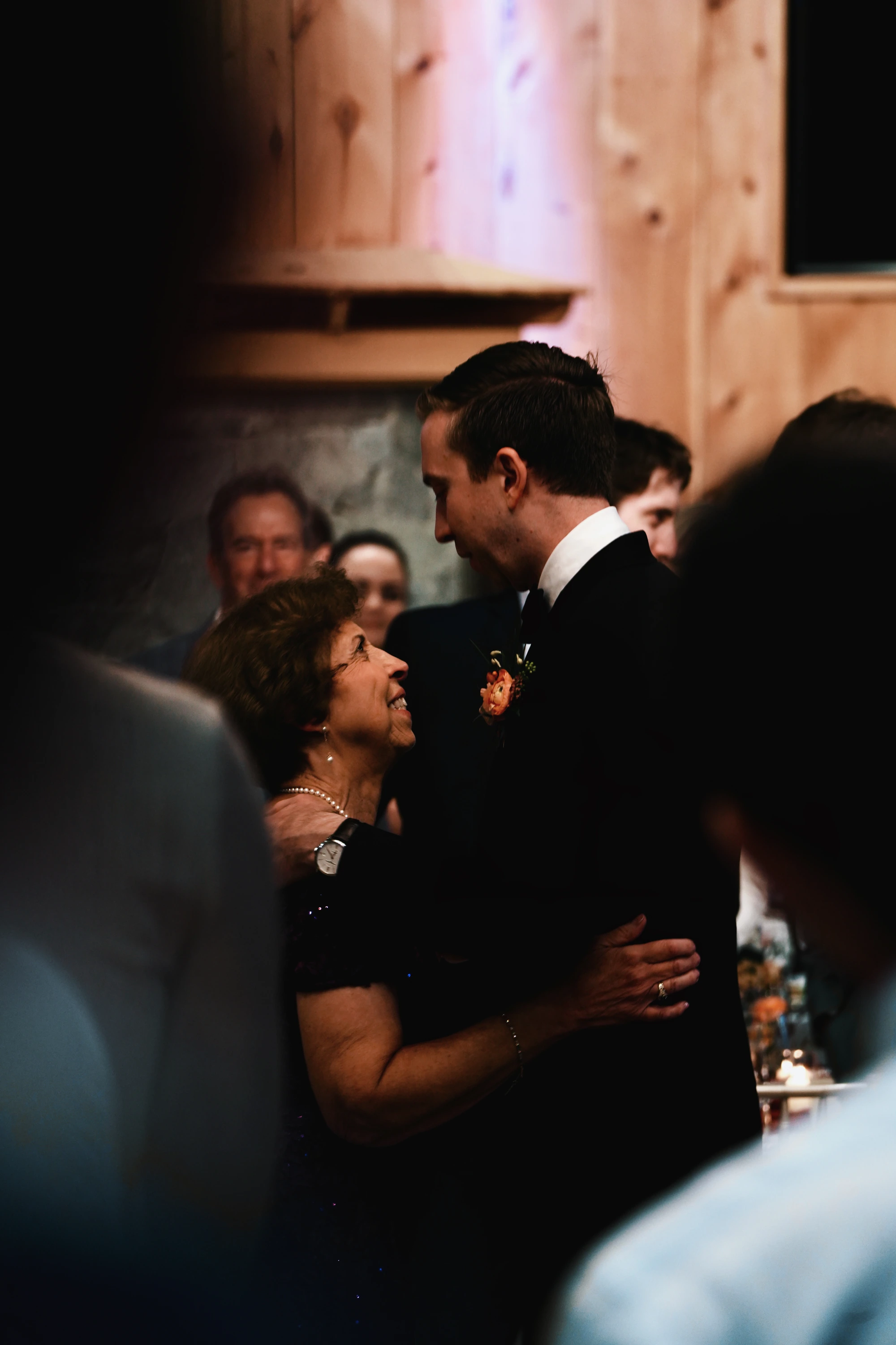 A groom dances with an older woman among guests.