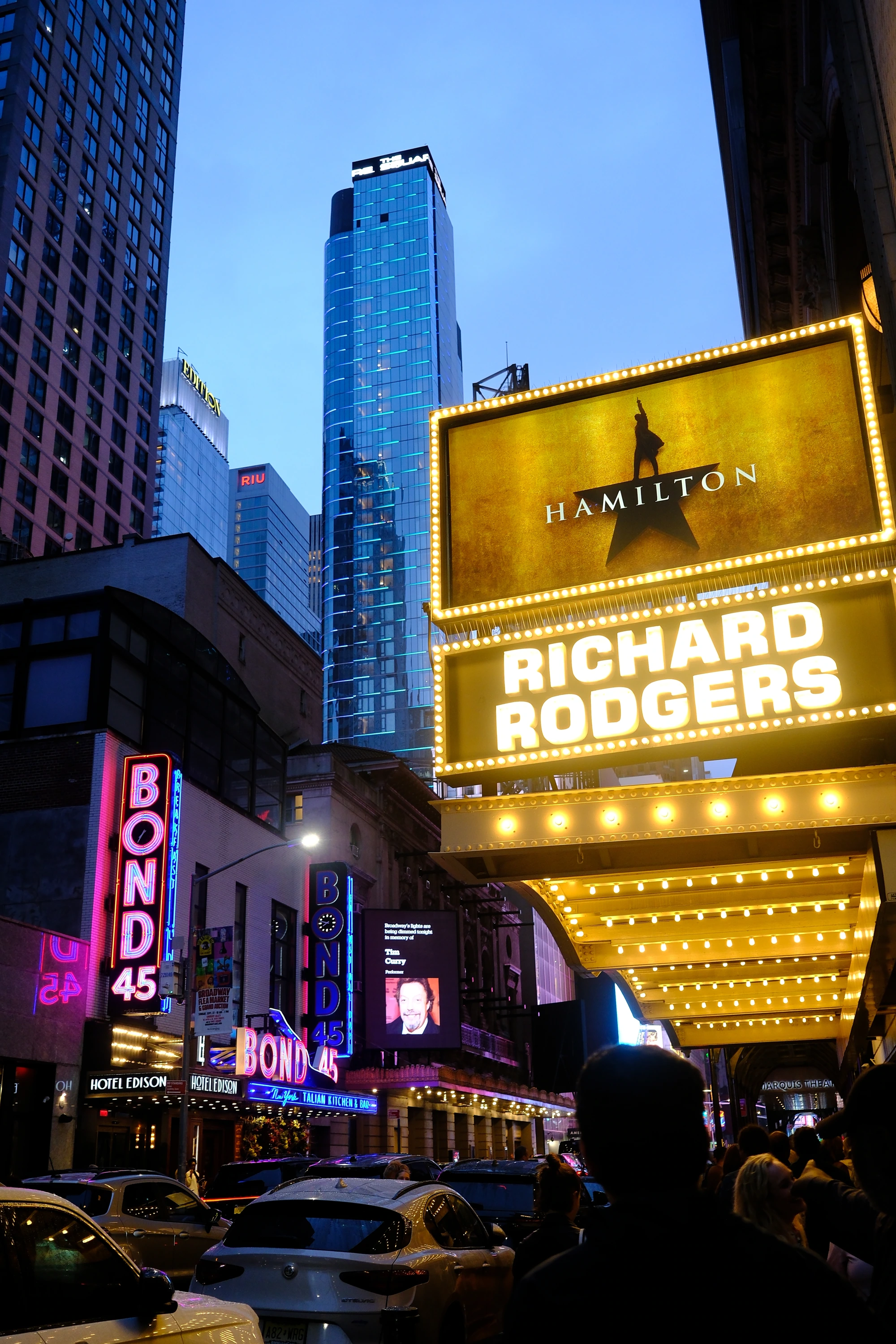 A glowing Hamilton marquee under Manhattan towers.