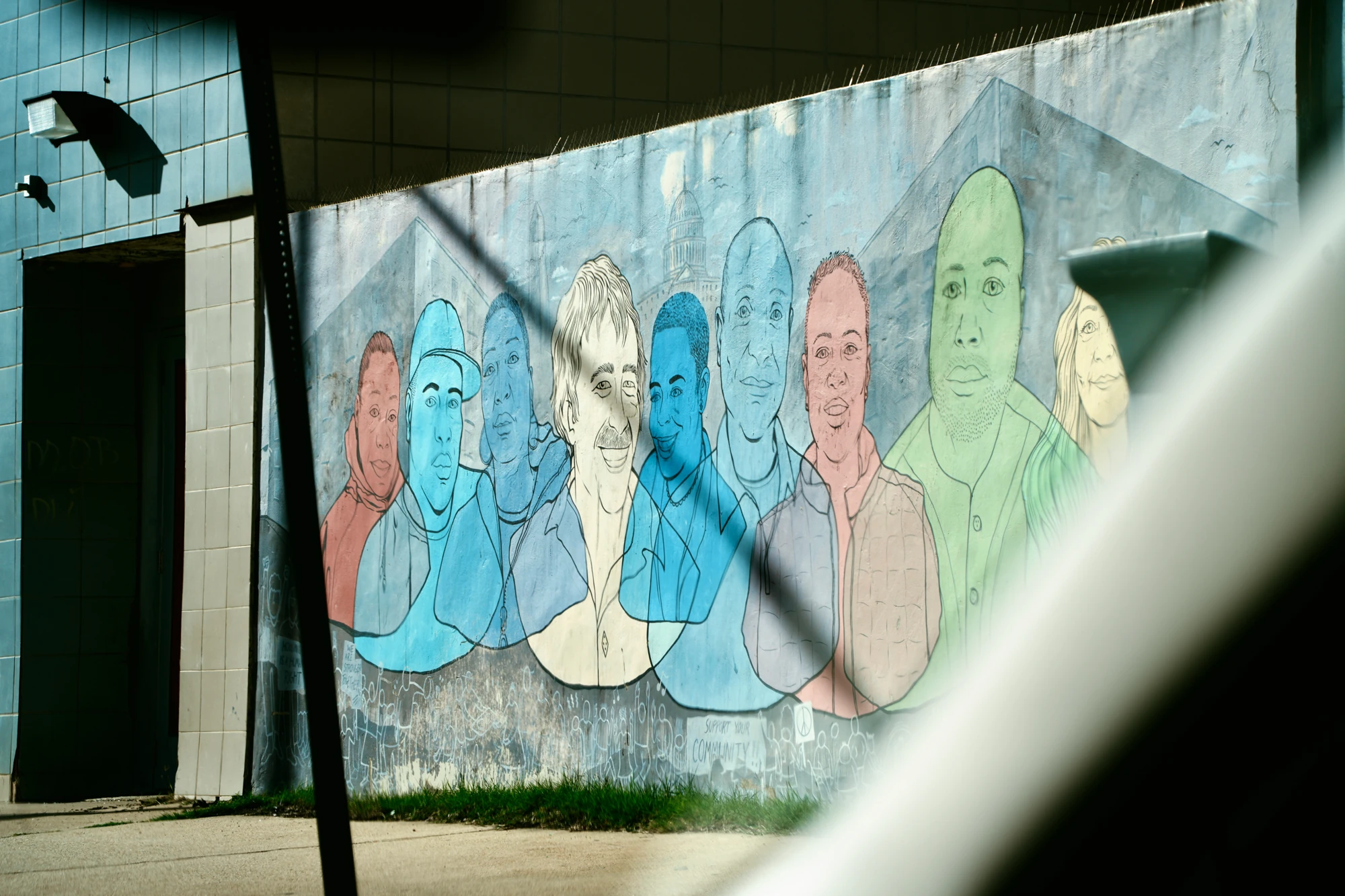 A mural of colorful faces is seen through a vehicle window.