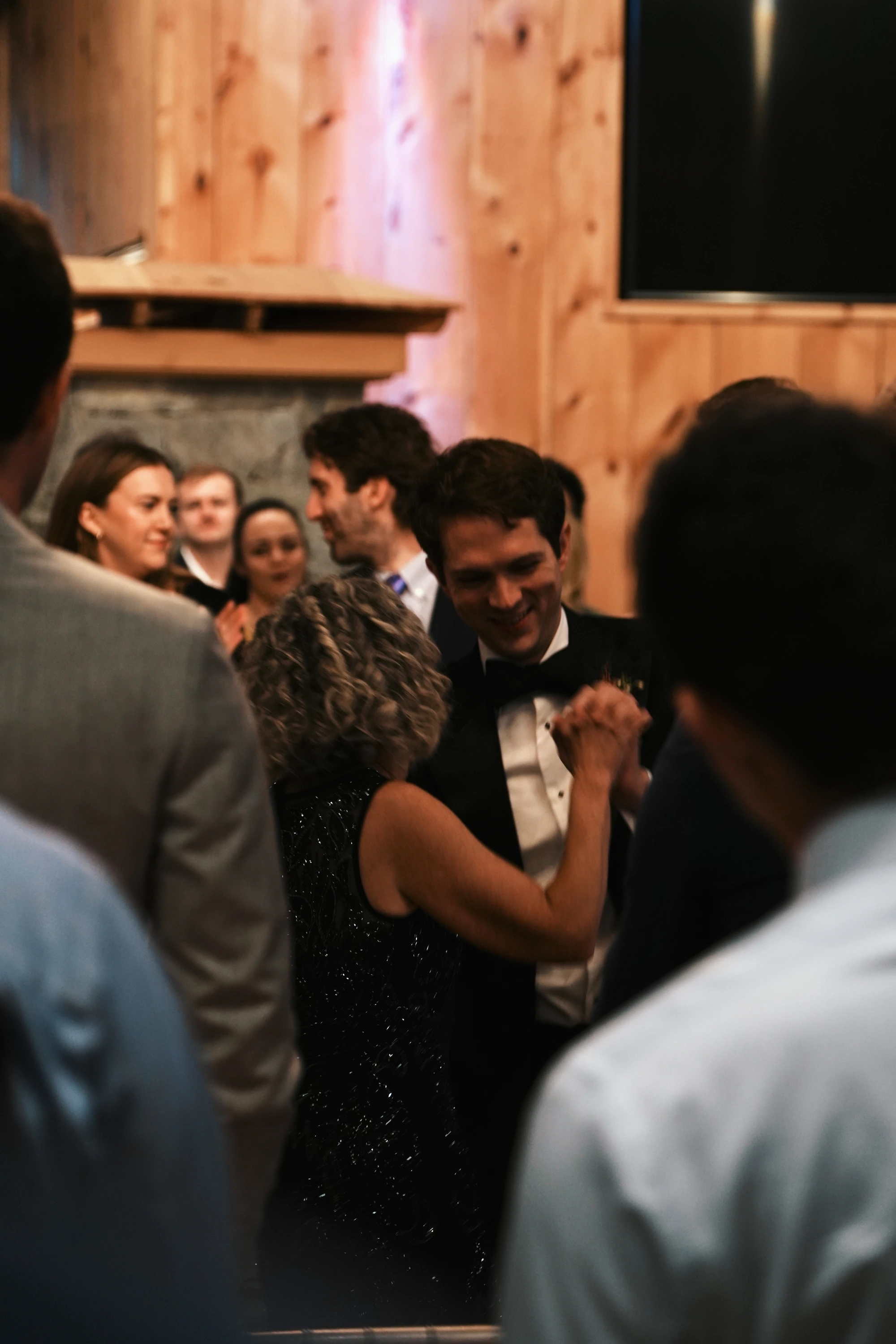 Guests laugh and dance close together at a wedding.