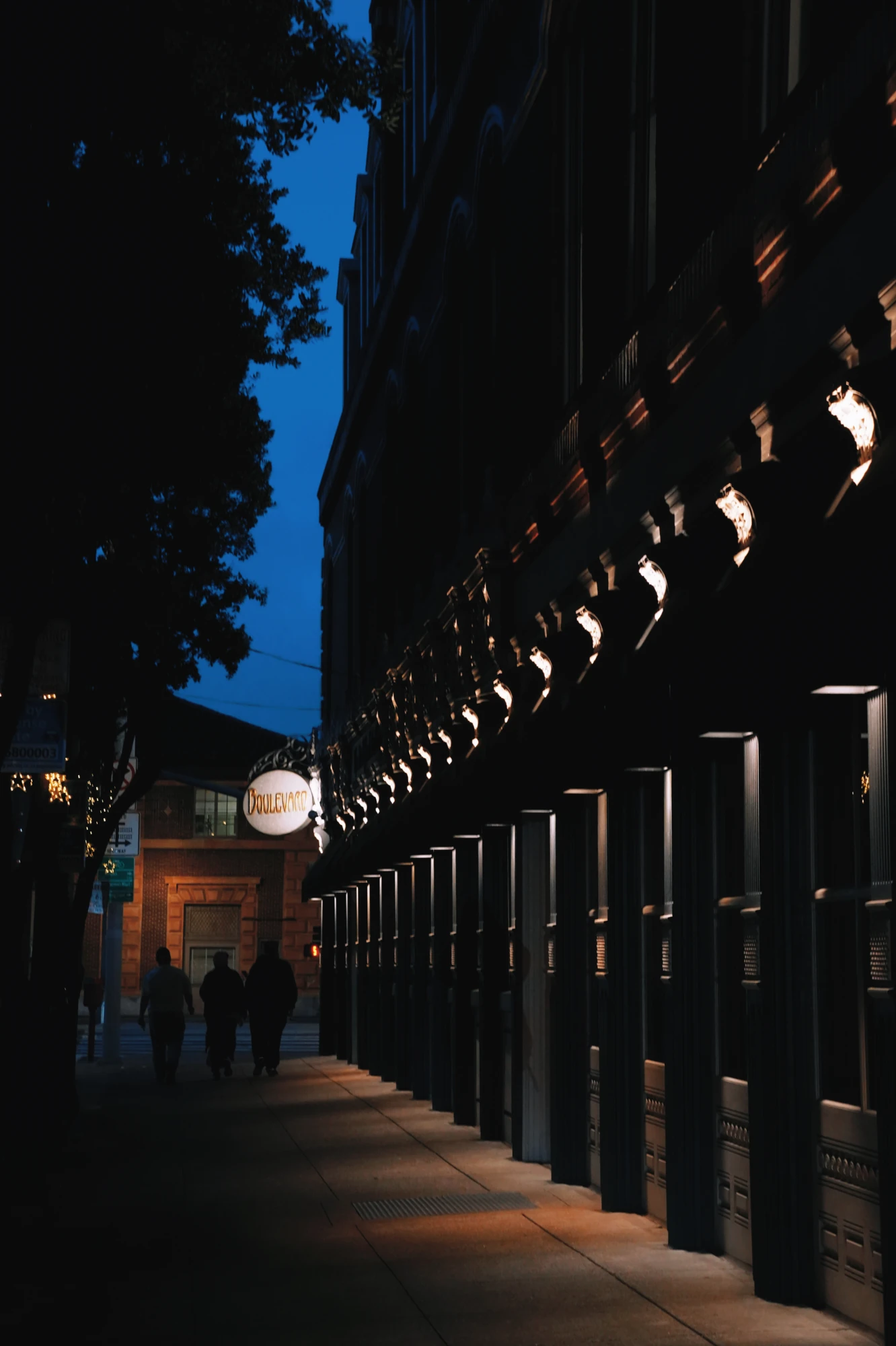 An illuminated arcade recedes into a dark blue evening.