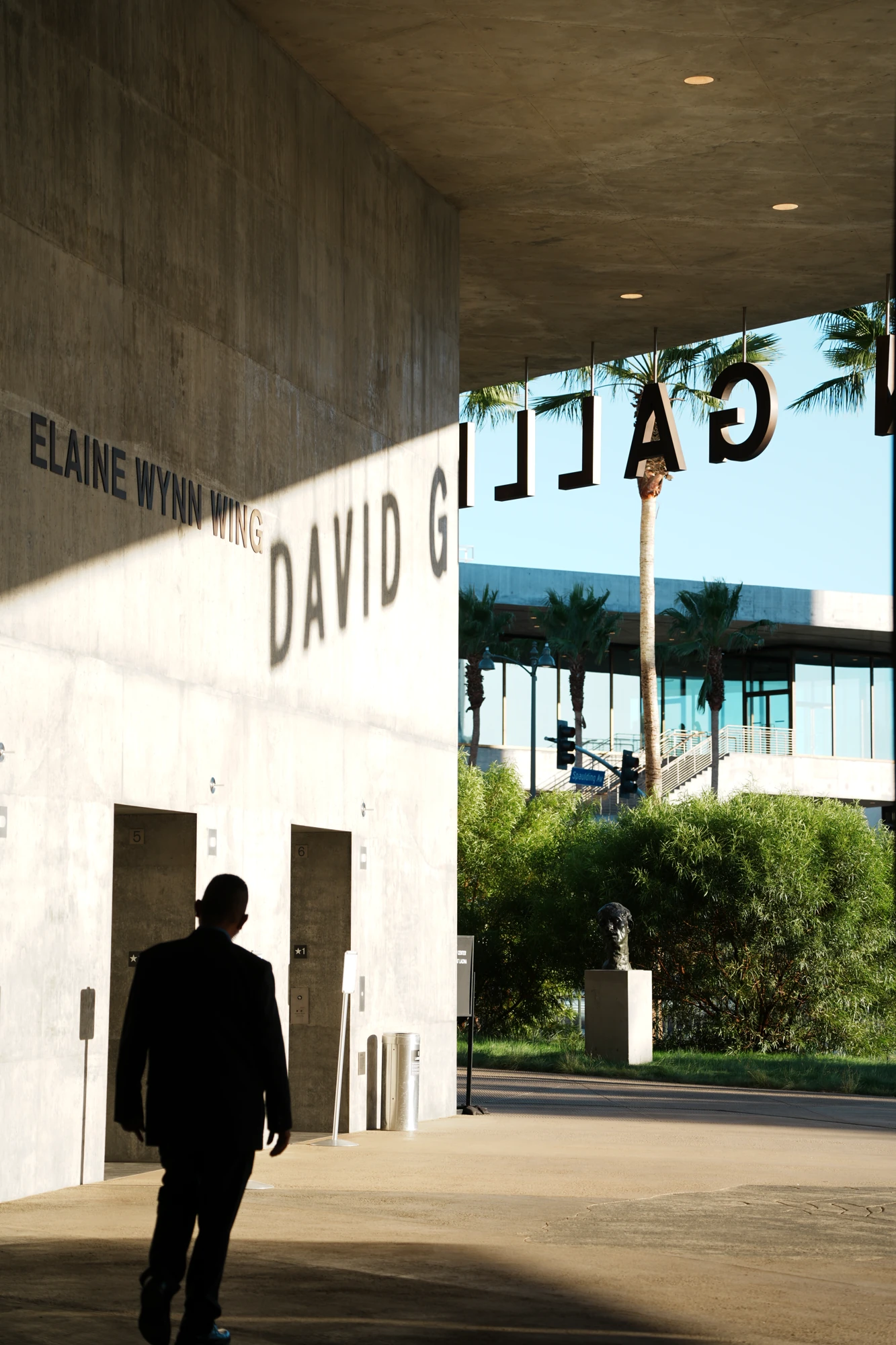 A silhouette pauses inside a sunlit concrete passage.