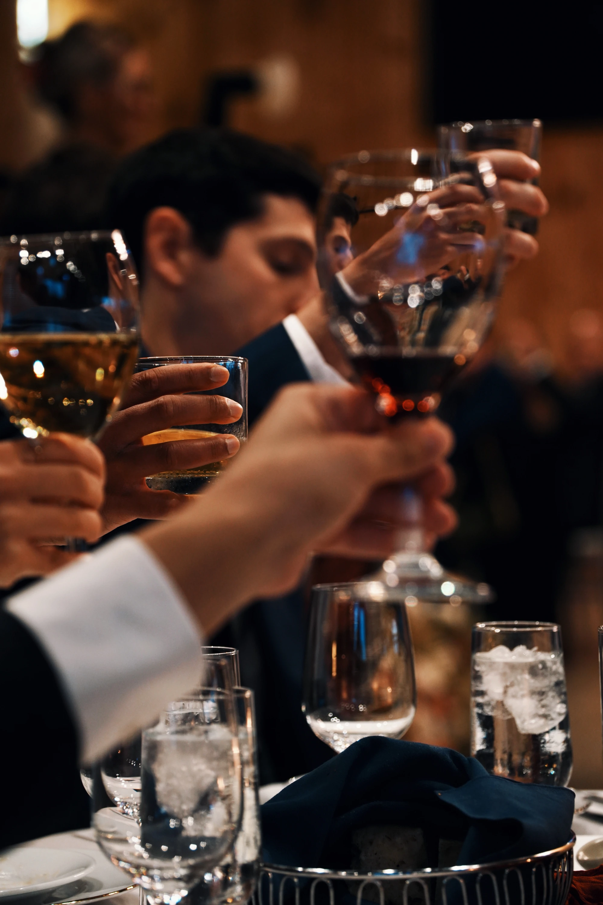 Guests raise glasses around a candlelit dinner table.