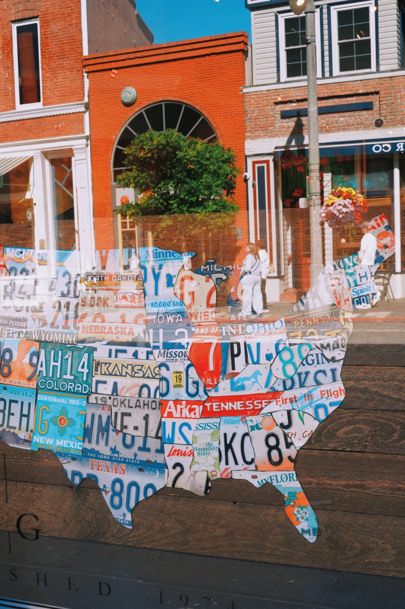 A map assembled from license plates is displayed outside a brick building.