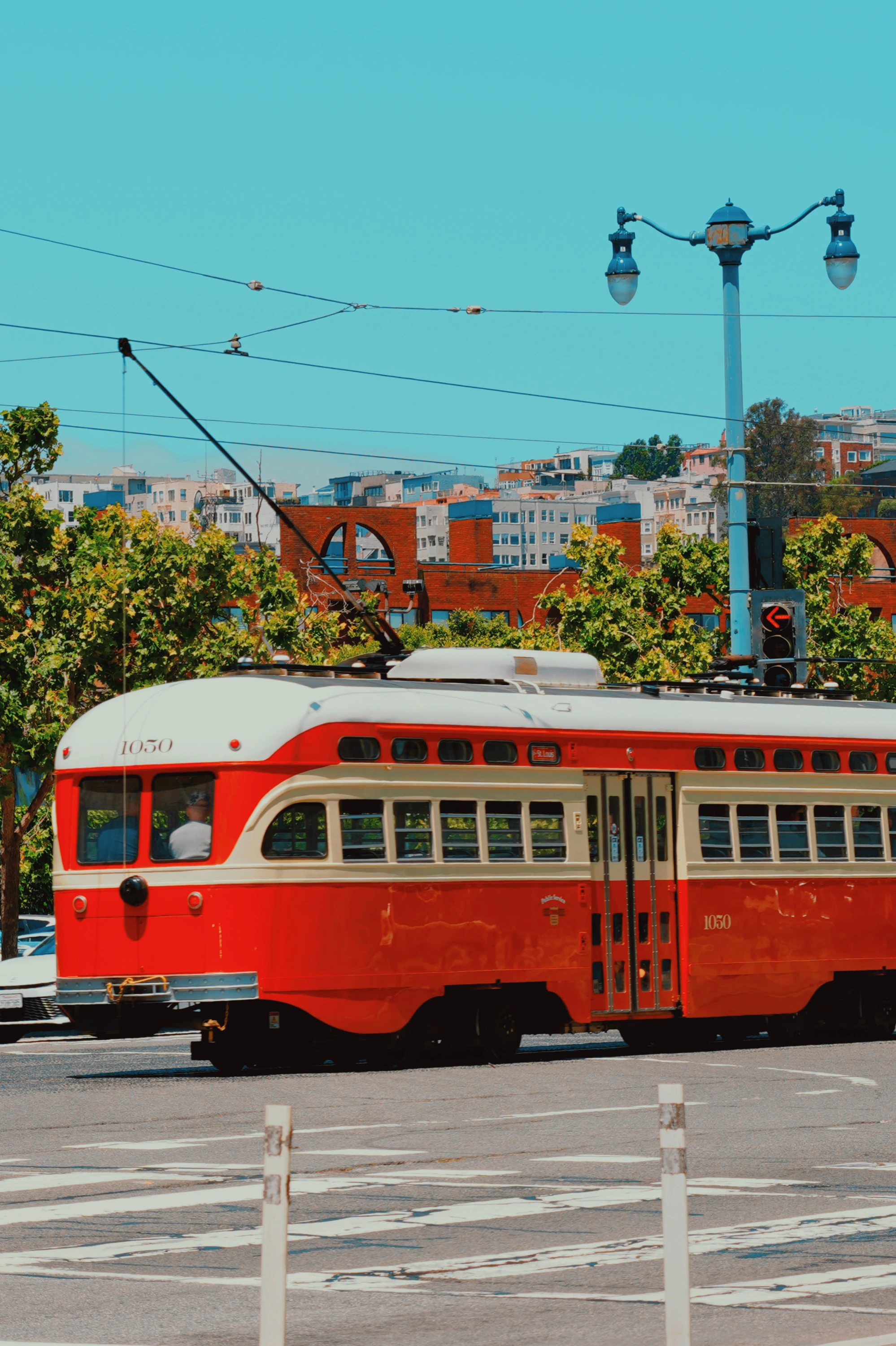 A red heritage streetcar crosses an intersection under blue sky.